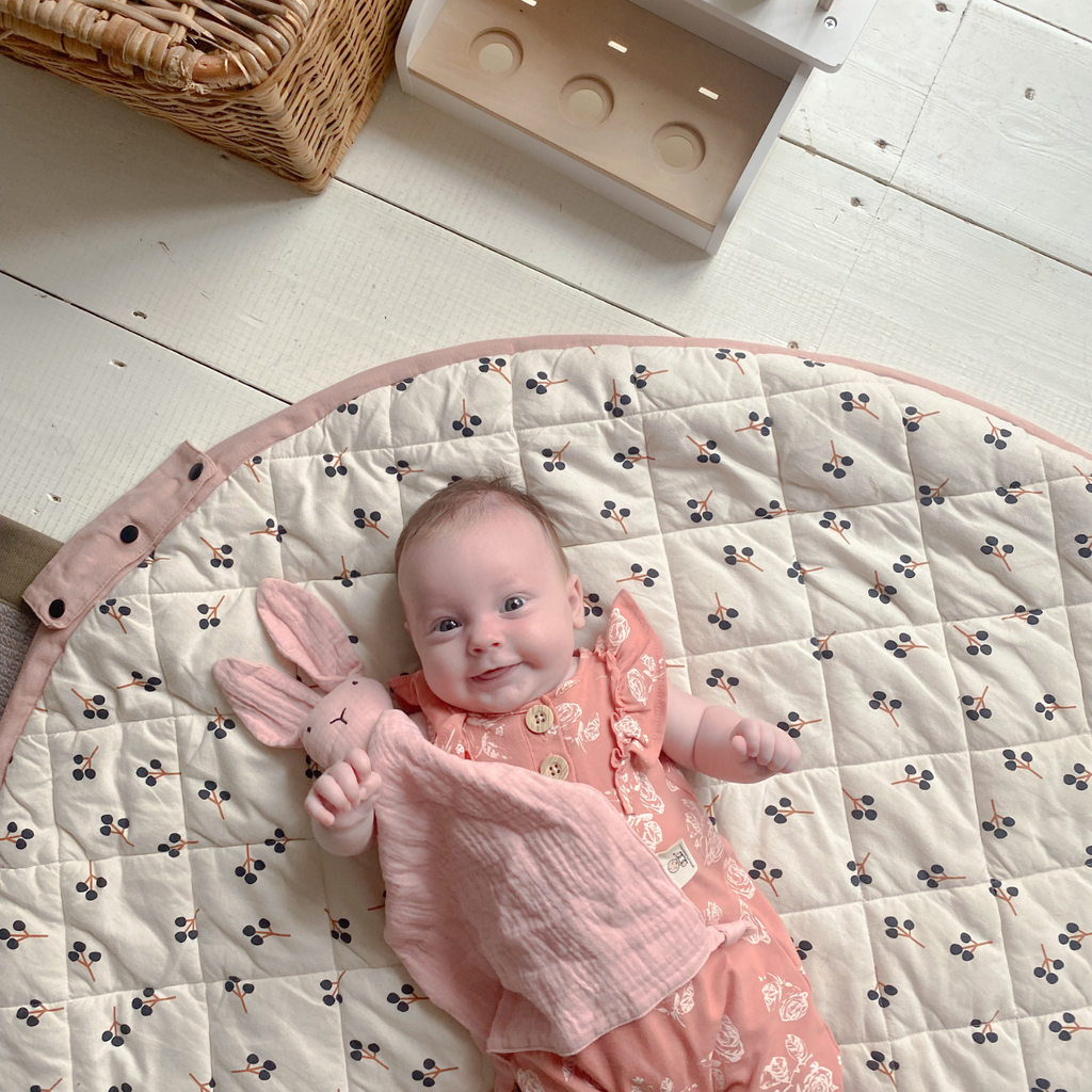 Baby girl looking really happy with her muslin bunny comforter in pastel pink. That's a review in itself.